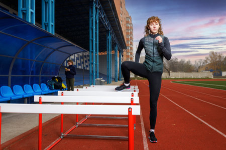 Sportswomen at the athletics training with hurdles at the stadiumの写真素材