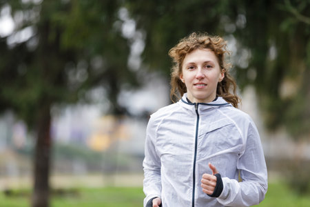 Young woman running in autumn park in the morningの写真素材