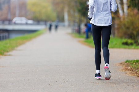 Back view of young woman running in the park in the morningの写真素材
