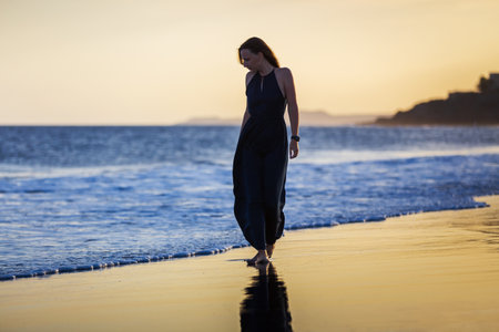 Young lady in long dress enjoying the evening at the beachの写真素材