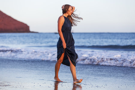 Young lady in long dress enjoying the evening at the beachの写真素材