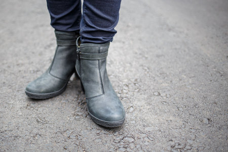 Young woman wearing nice boots standing on the asphalt surfaceの写真素材