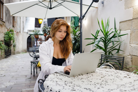 Young redhead woman using laptop in the cafe. Student girl browsing on internetの写真素材