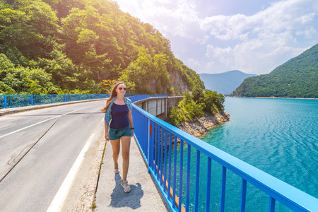 Young woman walking on the bridge across Piva lake in Montenegroの写真素材