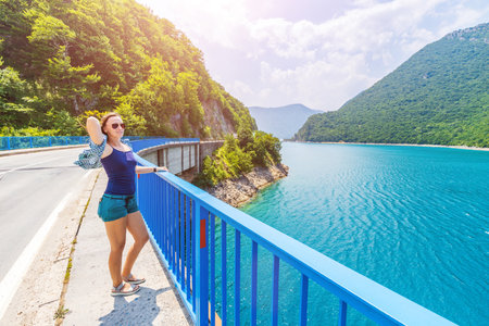 Young woman walking on the bridge across Piva lake in Montenegroの写真素材