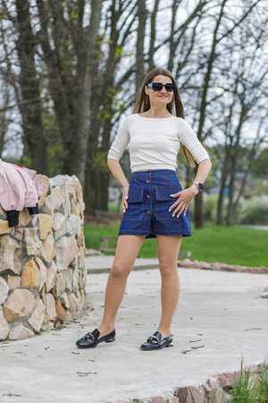 Young woman in short denim skirt and blouse walking along the lakeの写真素材