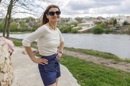 Young woman in short denim skirt and blouse walking along the lakeの写真素材