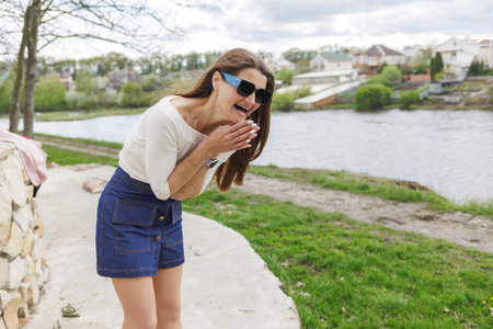 Young woman in short denim skirt and blouse walking along the lakeの写真素材