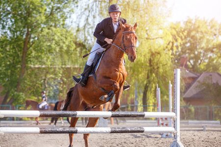 Young sportsman riding horse bounding over an obstacle on showjumping competition. Image with copyspaceの写真素材