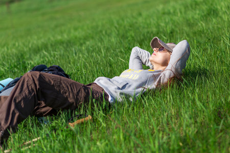 Young tourist woman taking a rest on green hill lying in the grass