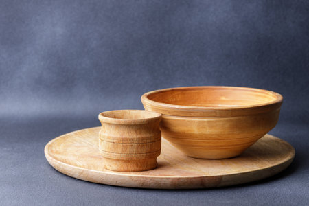 Wooden Seasoning Mortar and Clay Handmade Bowl on a Round Platter Against a Dark Background.の写真素材