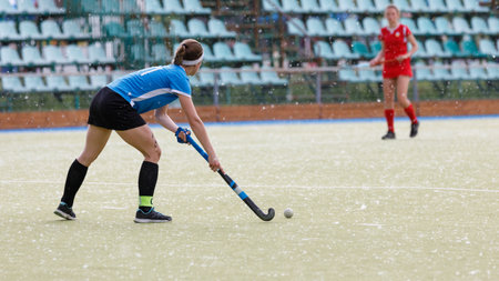 Female hockey player leading the ball during a match in a stadium