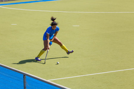 Young female field hockey player passing the ball through the pitchの写真素材