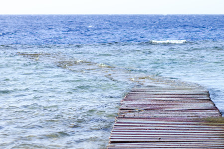 Serene old wooden dock extending into tranquil blue ocean waterの写真素材