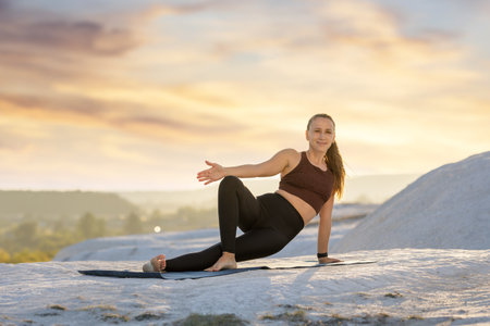Yoga practice at sunset on rocky terrain near a scenic landscapeの写真素材