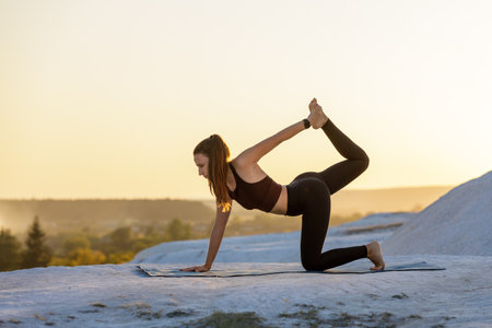 Yoga practice at sunset on a mountain with a serene atmosphereの写真素材