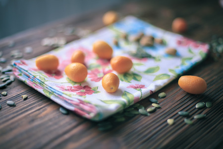 Kumquats on wooden table soraunded by pupmkin seedの写真素材