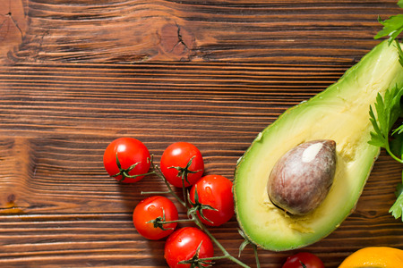 Guacamole on wooden table surrounded by its ingridientsの写真素材