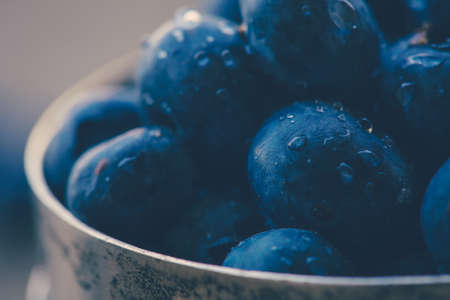 Old bowl of fresh organic blueberries on wooden table.Soft focus, retro filter.の写真素材