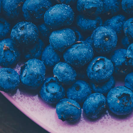 Old bowl of fresh organic blueberries on wooden table.Soft focus, retro filter.の写真素材