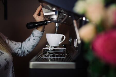 Coffee machine make espresso in cup. female barista preparing coffee in cafeの写真素材
