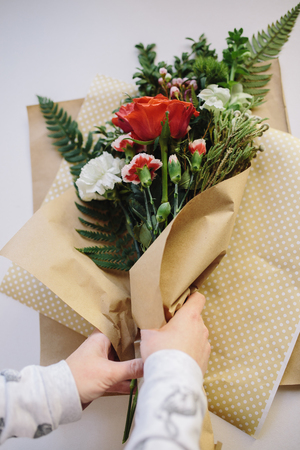 Hands making red and white flowers bouquetの写真素材