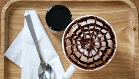 Art of hot coffee in white cup on wooden tray with spoon and paper, above viewの写真素材