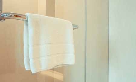 Clean white towel hanging on hanger or handle of glass doorの写真素材