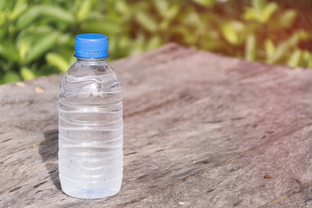 Plastic water bottle on wooden table texture with nature background.  scene of summer season. Fresh concept.の写真素材