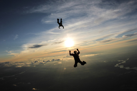 Two skydivers are flying in the sunset sky.の写真素材