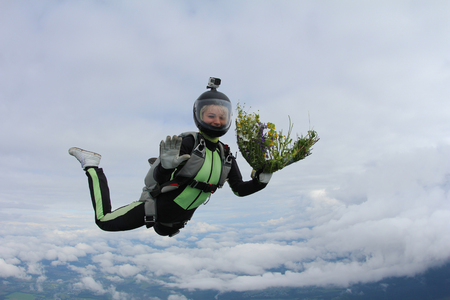 Skydiving girl with flowers is flying in the sky.