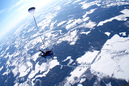 A tandem is in the sky above the winter ground.の写真素材