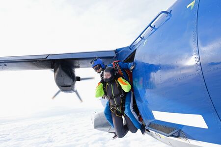 Skydiving. Tandem jump. Man and girl are flying out of a plane. First step.の写真素材