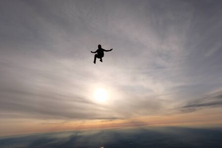 Skydiving. A skydiver is sitting in the sunset sky.