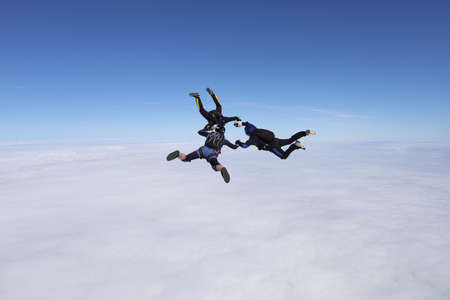 Skydiving. Three skydivers are in the sky.
