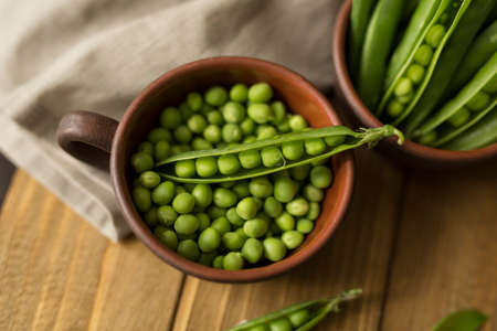 glay mug with fresh green peas on table with a piece of apronの写真素材