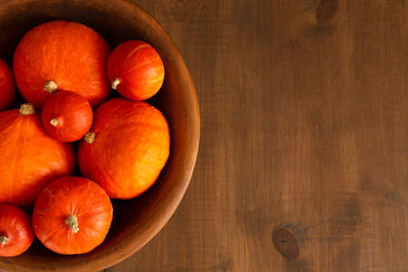 autumn harvest concept pumpkins in a big wooden bowl on a wooden background Flat lay horizontalの写真素材