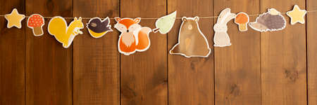 Garland of autumn children's figurines - star mushroom squirrel hedgehog Fox leaf bear hare on a wooden background Banerの写真素材