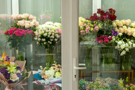 Refrigeration room for flowers in the store. Showcase outside view. Showcase behind glass. Bouquets of flowers, roses, gypsophila and other plants. horizontal photoの写真素材
