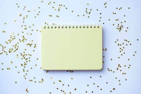 Yellow blank notepad on spirals on a festive white christmas background with gold sparkles. View...