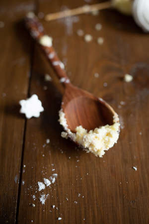 A wooden spoon is stained with cake on a wooden background after a cake wreck by a child. Celebration and fun ending conceptの写真素材