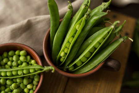 The concept of proper nutrition. mug with fresh green peas on table with a piece of apronの写真素材