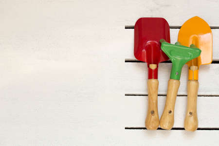 Used colored kids garden tools on white boards and white wooden background. Place for text. Flat layの写真素材