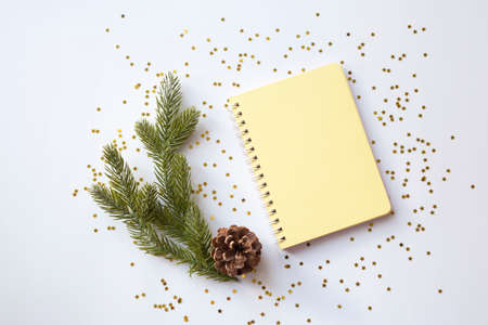 Yellow blank notepad on spirals on a festive white christmas background with gold sparkles. View from above. Place for your text. Ideal for New Yearの写真素材