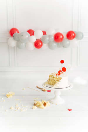 Festive location with the first birthday cake white background with red grey white balloons. place for text. holiday end concept. Smash cakeの写真素材