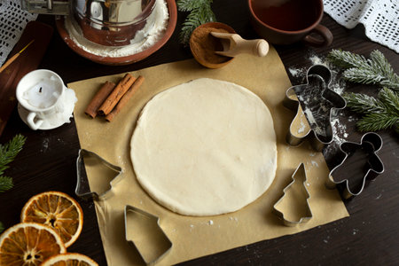 Culinary Christmas background with baking ingredients - round sheet of dough on the paper, flour, cookie cutters, rolling pin, dried orange, cinnamon. Flat layの写真素材