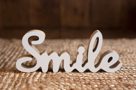 Wooden white figure of the word smile on a woven straw rugの写真素材