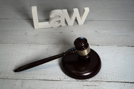 Law concept - Open law book with a wooden judges gavel on a courtroom or law officeの写真素材