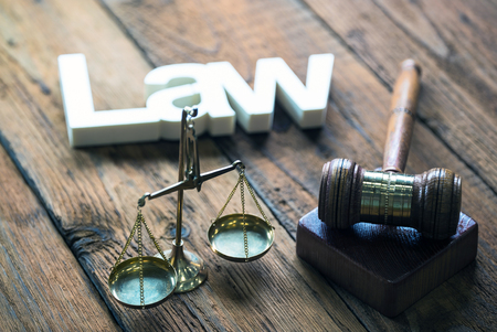 Law concept - Open law book with a wooden judges gavel on a courtroom or law office