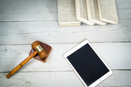 Law concept - Open law book with a wooden judges gavel on a courtroom or law officeの写真素材